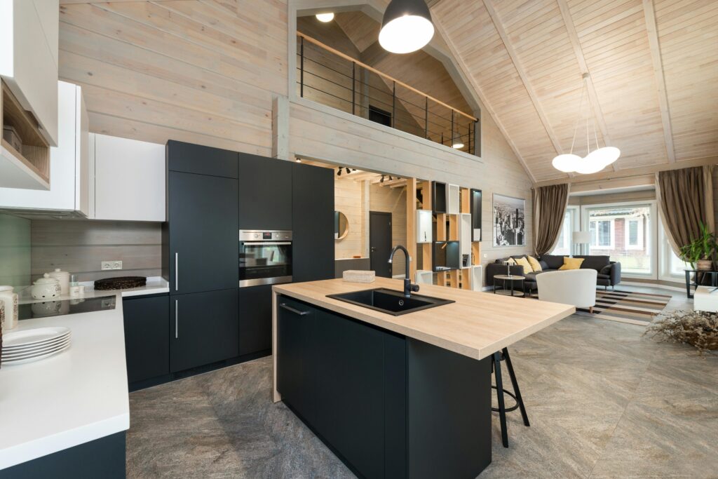 Stylish matte furniture and built in appliances under glowing lamp hanging on wooden ceiling with living zone in spacious house