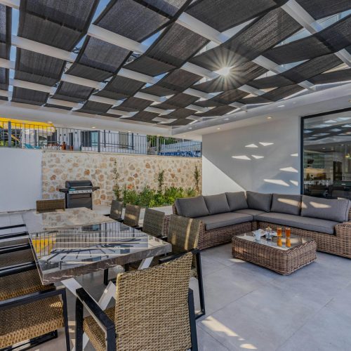 Elegant outdoor patio featuring modern wicker furniture with a sunlit geometric roof.